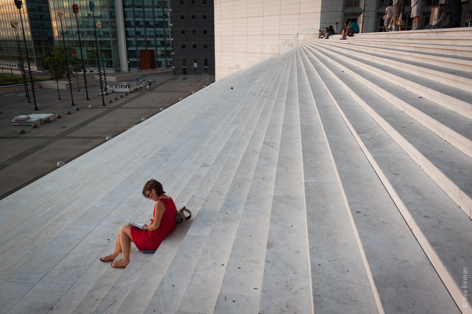 People sit on the steps of the Grande Arche in Paris